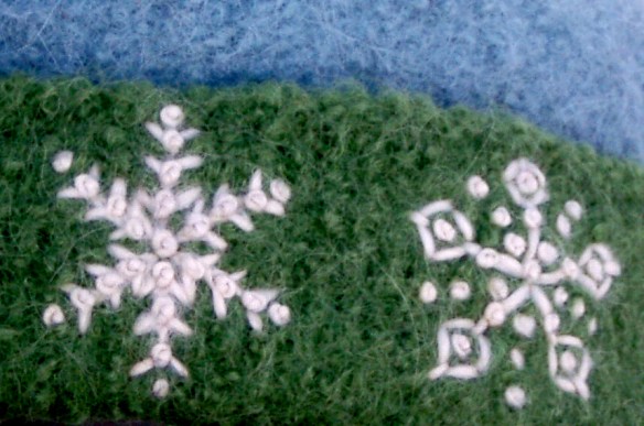 Detail of freehand embroidered french knot snowflakes on a green and blue felt hat by fiber artist, Carrie Cahill Mulligan, of Canaan, New Hampshire
